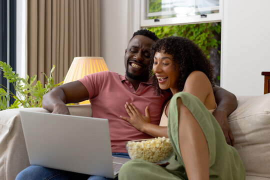 Biracial African American couple laugh while using a laptop at home