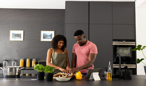Biracial African American couple are cooking together in a modern kitchen at home