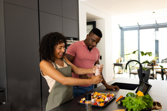 Biracial African American couple are cooking together in a modern kitchen at home