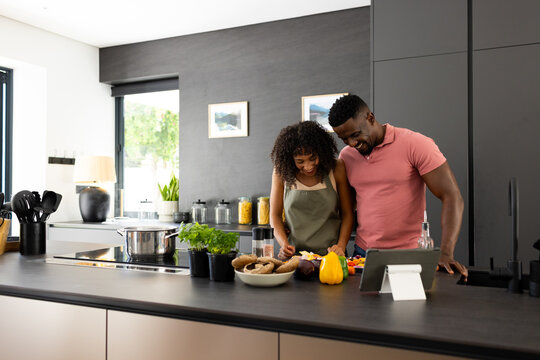 Biracial African American couple are cooking together in a modern kitchen at home with copy space