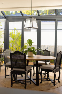 A well-lit dining area at home features a wooden table surrounded by black chairs