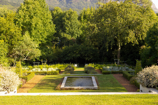 A manicured garden features a central water fountain surrounded by lush greenery at home, with copy 