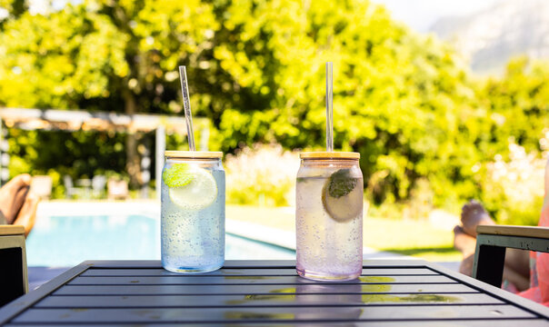 Two glasses with refreshing drinks and straws are on an outdoor table