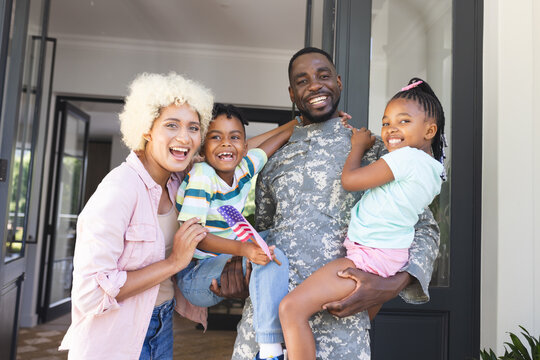 African American soldier in military uniform with his family outside their home