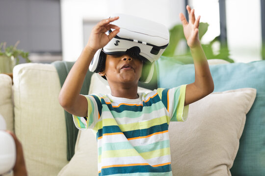 African American boy wearing a virtual reality headset, gesturing with his hands - Powered by Adobe