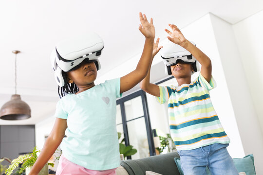 African American sister and brother are engaged in a virtual reality game, wearing VR headsets