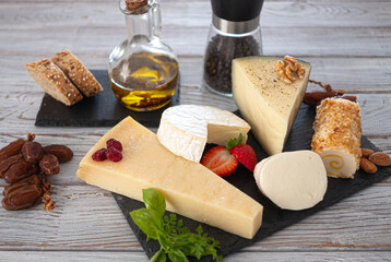 Set or assortment of cheeses. Parmesan, mozzarella, Spanish goat cheese, brie and roll with almonds and pineapple. On wooden background. copy space