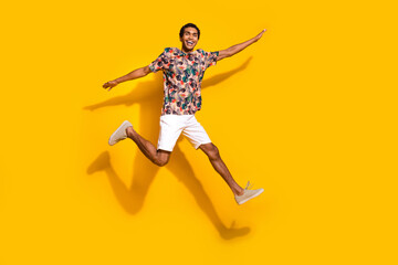 Fototapeta na wymiar Full length photo of carefree cool guy dressed print t-shirt jumping high arms sides empty space isolated yellow color background