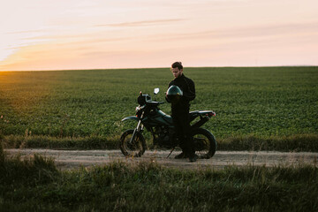 motorcyclist on an enduro motard motorcycle in a field at sunset