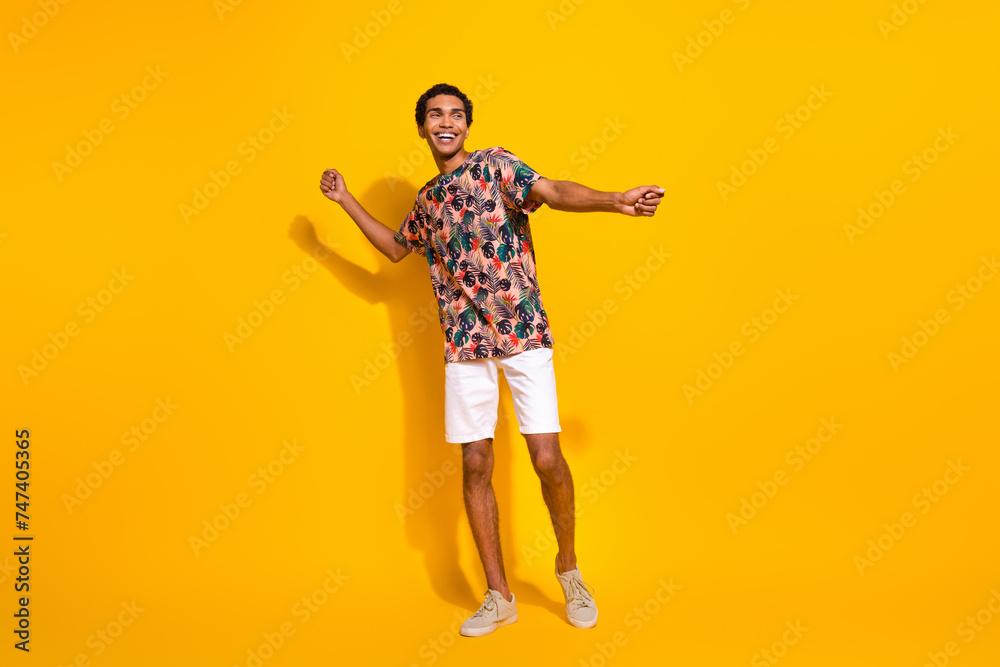 Wall mural Full body length size photo of funky young man in t shirt with white shorts discotheque summertime isolated on yellow color background