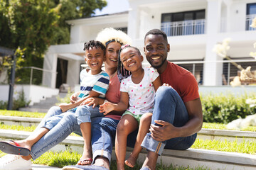 African American man and young biracial woman sit with a boy and a girl, all smiling