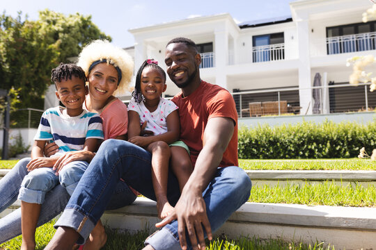 Diverse family enjoys time together outdoors, with a modern home in the background