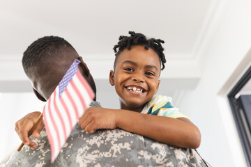 African American boy with a bright smile is being held by a soldier