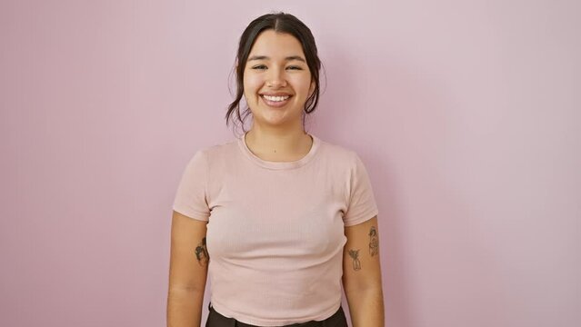 Excited young hispanic woman standing confidently, flaunting a cool, happy smile over an isolated pink background. perfect teeth glowing amidst her joy-filled, radiant face