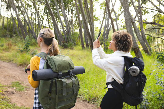 Young Caucasian woman and biracial woman explore a forest trail on a hike