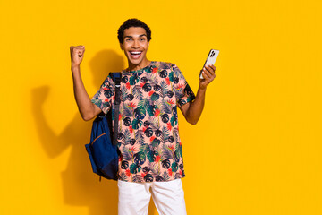 Photo of young guy raised fist up winning free access for student premium application smartphone isolated on yellow color background