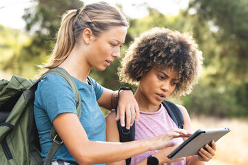 Two women are examining a tablet outdoors during a hike