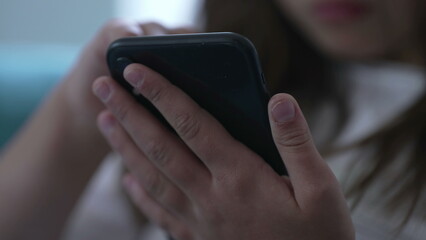 Close-up child's hands holding cellphone device. Kid using modern technology staring at phone screen browsing social media