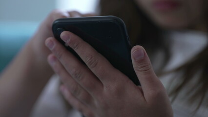 Close-up child's hands holding cellphone device. Kid using modern technology staring at phone...