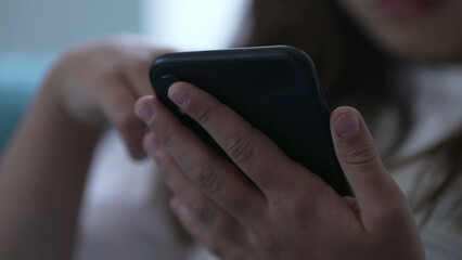 Close-up child's hands holding cellphone device. Kid using modern technology staring at phone screen browsing social media