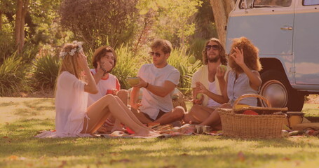 Group of diverse friends having lunch and enjoying in the park while having a picnic