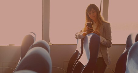 Caucasian businesswoman smiling while using smartphone standing in the bus