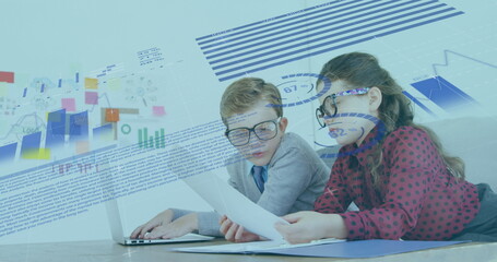 Image of financial data processing over schoolboy and schoolgirl working in an office together, usin