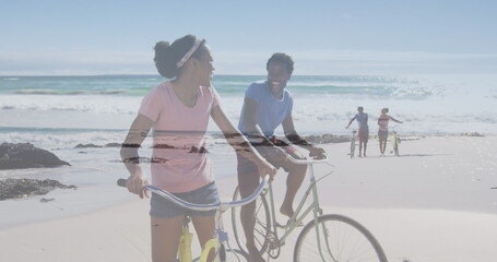 Image of happy african american couple with bikes over seascape