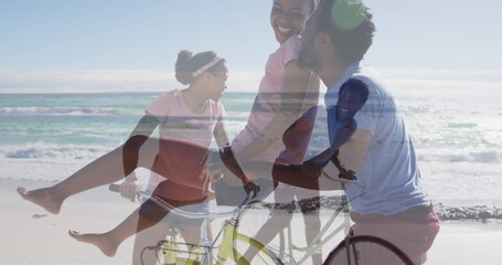 Image of happy african american couple with bikes over seascape