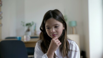 One pensive little girl having a breakthrough idea. Close-up face of a thoughtful child experiencing an eureka moment, indoors at home