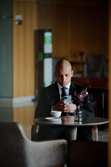 African american businessman using smartphone near coffee in lobby of business center