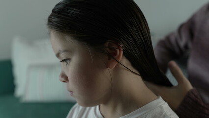 Parent combing child's hair at night routine before bedtime, close-up face of little girl while Mother combs hair
