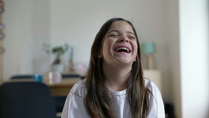One happy little girl bursts laughing out loud. Close-up child face feeling joy in carefree moment,...