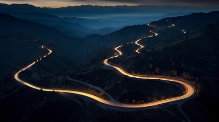 Aerial panoramic view of curvy mountain road with trailing lights at night