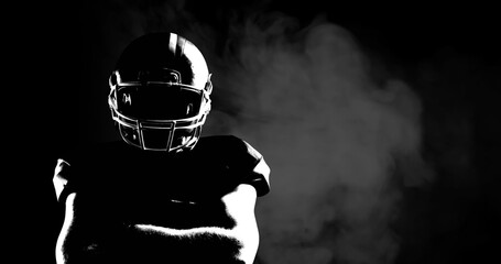 Image of smoke over male american football player with arms crossed