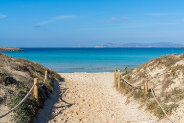 beach access leads to Ses Illetes beach on Formentera with a view of Ibiza and Es Vedra in the background
