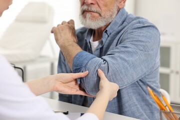 Arthritis symptoms. Doctor examining patient's elbow in hospital, closeup