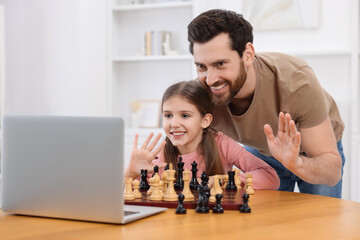 Father teaching his daughter to play chess following online lesson at home