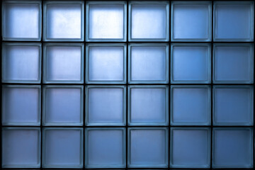 Window is made of a blue glass block glowing from the inside. Glass block wall pattern.