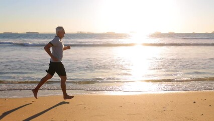 64 year old man getting his exercise at the beach at sunset. Slow Motion.