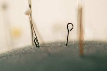 super close-up in a sewing workshop pin cushion is covered with needles and pins
