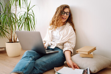 Young woman sit at home, using laptop computer, listening music with earphones. Freelance, online course. Shopping online. 