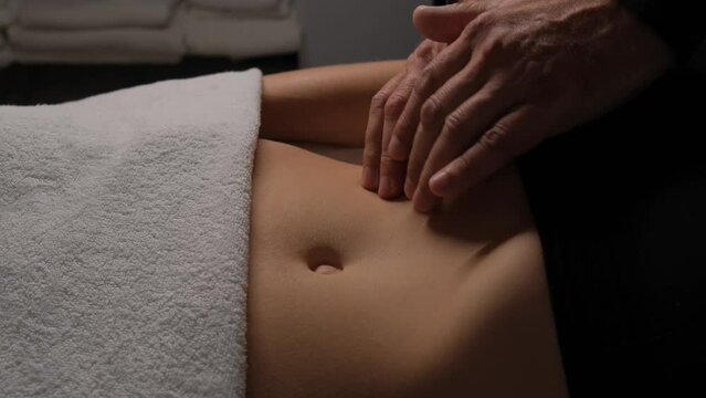 Male hands doing lymphatic drainage massage on a female stomach.