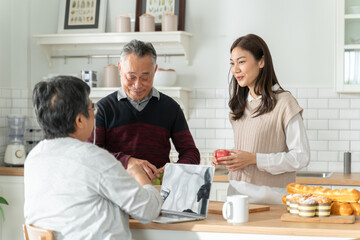 Fototapeta na wymiar young daughter look to old mother cook in kitchen.Beautiful female enjoy spend leisure time and hugging senior elderly mom peel mango on table in home.Asian lovely family,Activity relationship concept