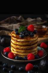 Delicious pancakes with fresh berries on dark background. Food concept.