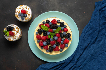 Homemade cake with fresh berries and sweet desserts on dark background.