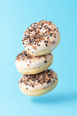 Different fresh donuts on blue background. Minimal food concept.