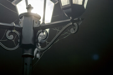 Vintage style 3 Hexagonal cone lantern lamps, white glowilluminating spider webs, black background.