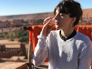 cute young girl drinking mint tea on a terrace in the adobe village of ait ben haddou in morocco...