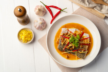 Steamed Seabass fish with Soybean Paste sauce in white plate.Top view